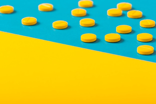 Free photo yellow round pills on two colored backgrounds