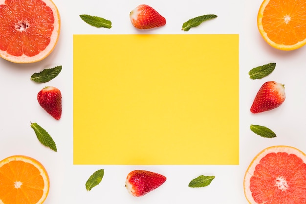 Free photo yellow sticky note sliced juicy grapefruit orange strawberry and green leaves