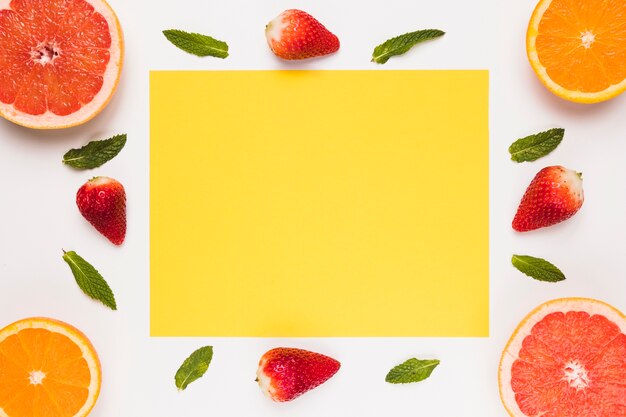 Yellow sticky note sliced juicy grapefruit orange strawberry and green leaves