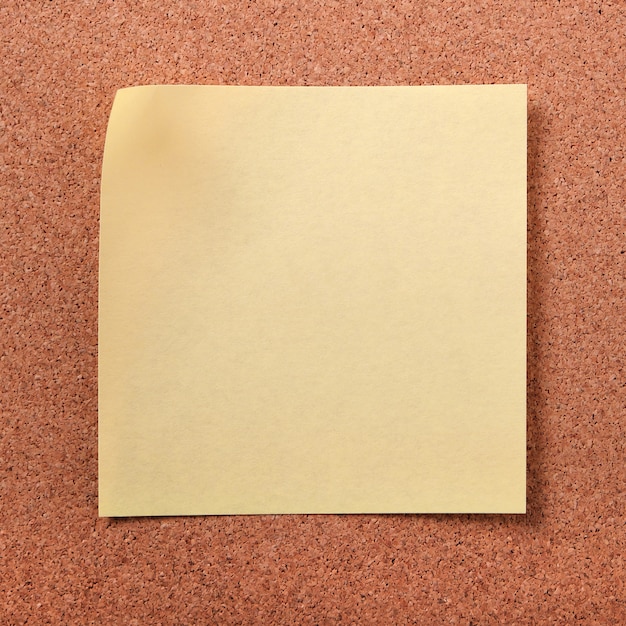 Yellow sticky post note on cork board
