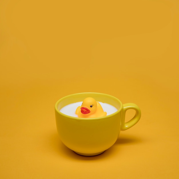Yellow still life of bath duck in cup of milk