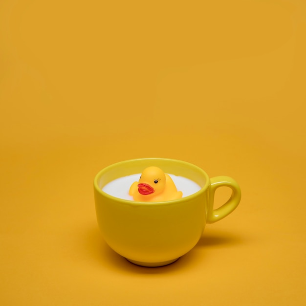 Free photo yellow still life of bath duck in cup of milk