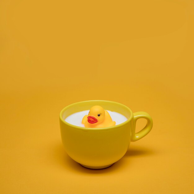 Желтый натюрморт ванны утки в чашке молока