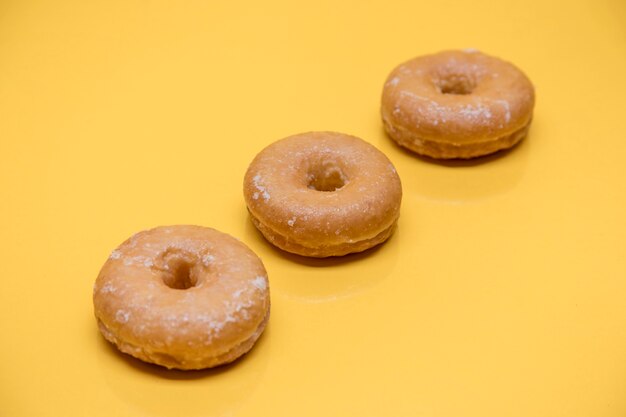 Yellow still life of three donuts