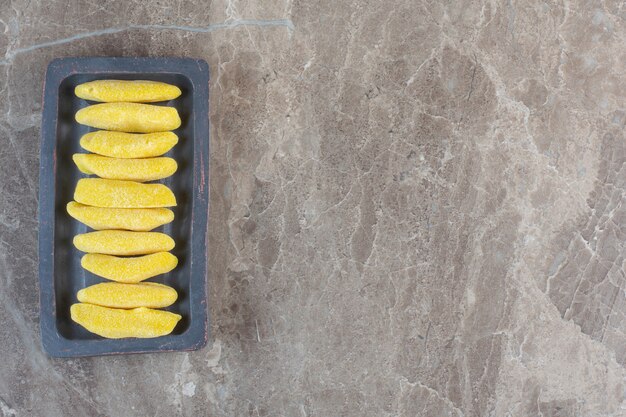 Yellow sweet candies in a row on wooden board.