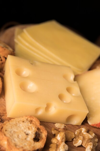 Yellow swiss cheese with bread slice and walnut on wooden surface