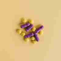 Free photo yellow tablets and purple capsules on textured background