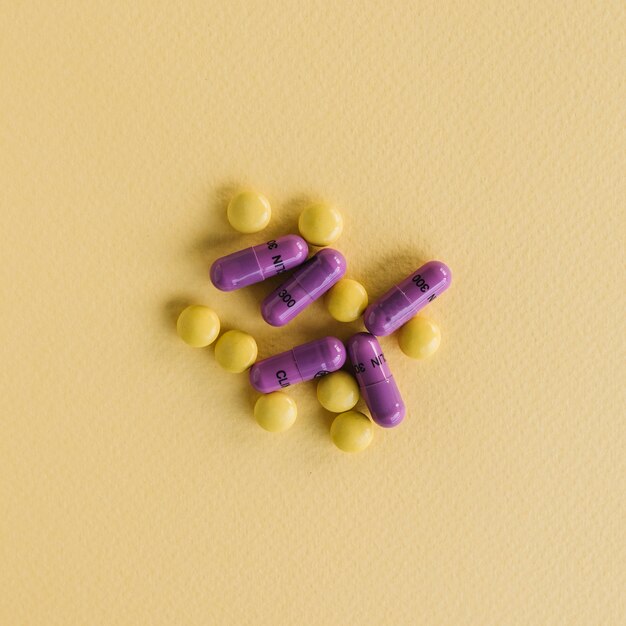 Yellow tablets and purple capsules on textured background
