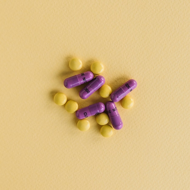 Yellow tablets and purple capsules on textured background