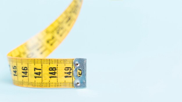 Yellow tape measure on blue background