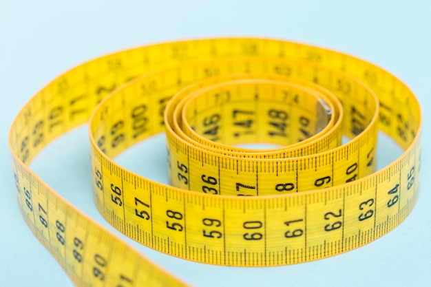 Yellow tape measure on blue background