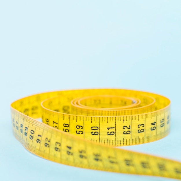 Yellow tape measure on blue background