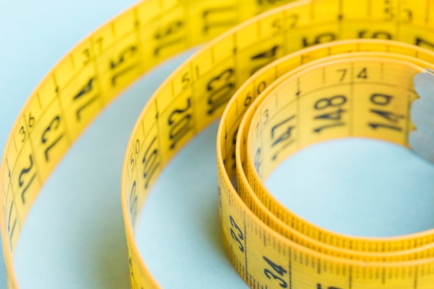 Yellow tape measure on blue background