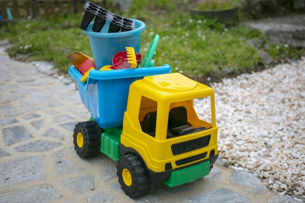 Желтый игрушечный грузовик во дворе