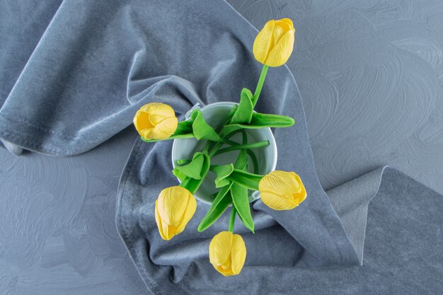 Yellow tulips in a bucket on piece of fabric , on the white background.