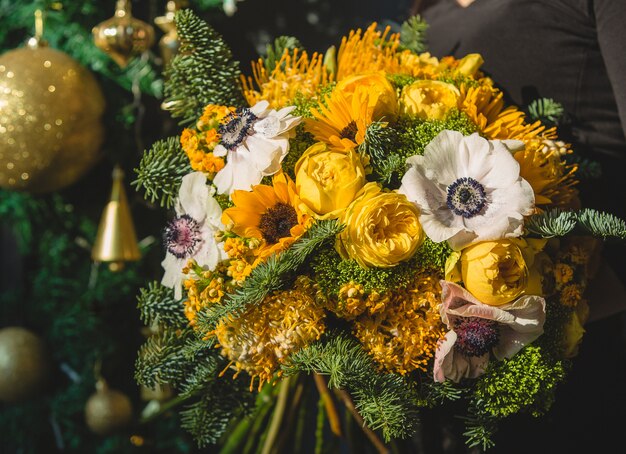 Yellow winter bouquet with golden christmas ornaments