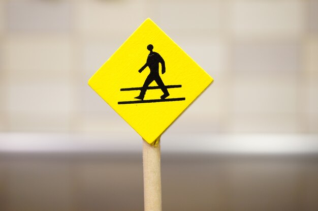 Yellow wooden toy sign with a walking person icon