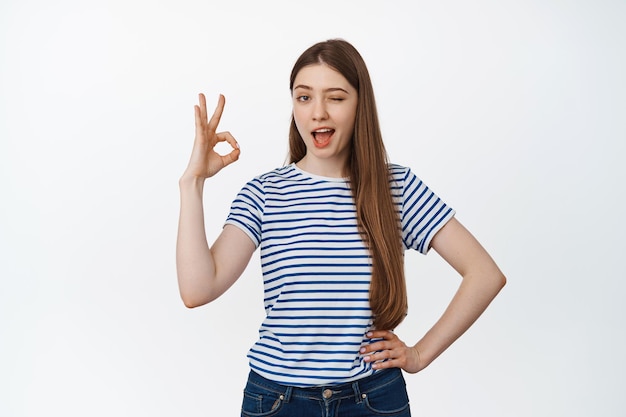 Yes. Smiling young woman assure you, showing okay, ok, confirmation gesture, give permission, approve and like smth good, white background