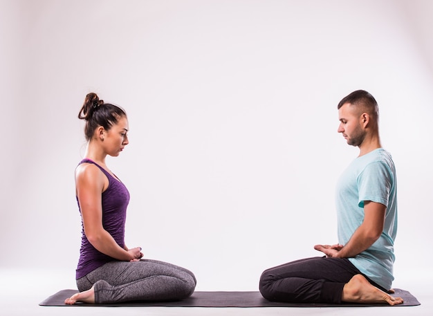 Yoga concept. Young healthy couple in yoga position on white background