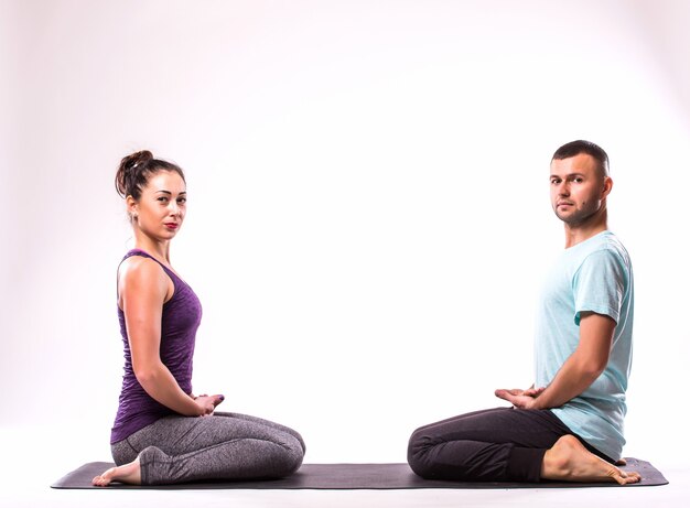 Концепция йоги. Молодая здоровая пара в позе йоги на белом фоне