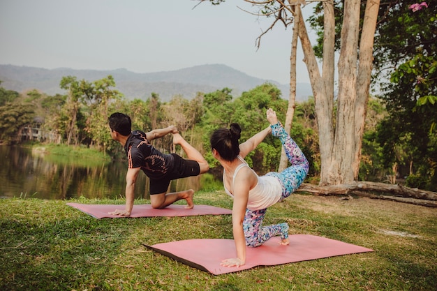 Free photo yoga lovers stretching next to the lake