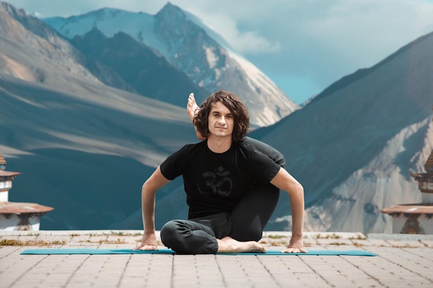 Uomo di yoga giovane che fa yoga in loft all'alba