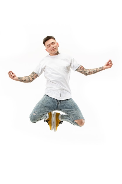 Йога в движении. Снимок в воздухе красивый счастливый молодой человек прыгает и позирует в асанах на фоне белой студии. Бегущий парень в движении или движении.