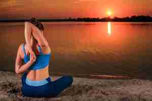 Free photo yoga at sunset on the beach. woman doing yoga, performing asanas and enjoying life on the river