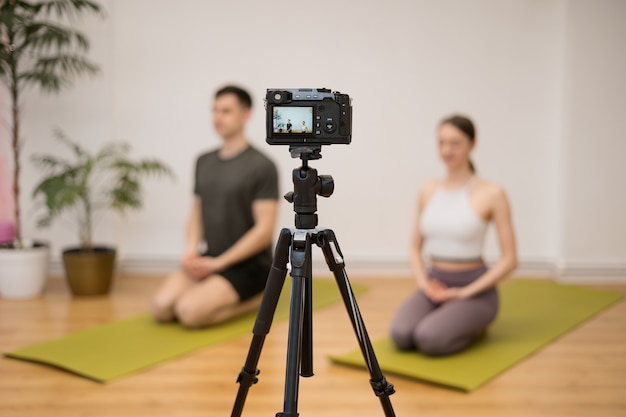 Тренер по йоге преподает онлайн-программу обучения в домашней студии за камерой. Спортивные инструкторы показывают позы йоги, объясняют, дают еще несколько советов.