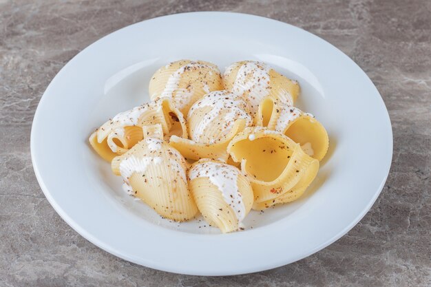 Yogurt on spicy pasta on the plate, on the marble surface.