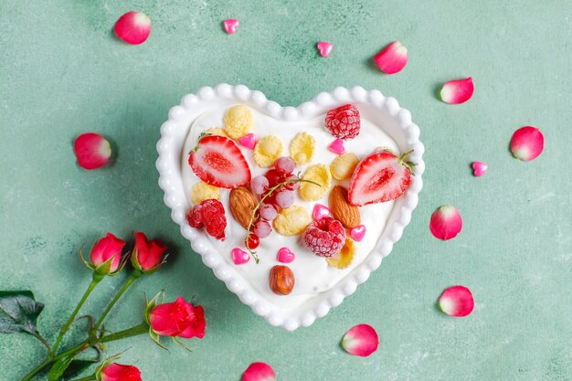 Yogurt with corn flakes and berries in a heart-shaped bowl.