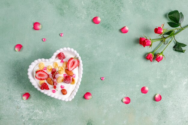 Йогурт с кукурузными хлопьями и ягодами в миске в форме сердца.