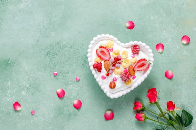 Йогурт с кукурузными хлопьями и ягодами в миске в форме сердца.