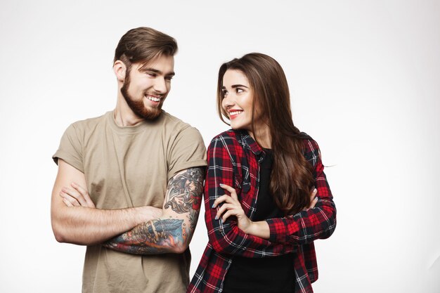 Yong tattooed man and nice woman standing crossing their hands.