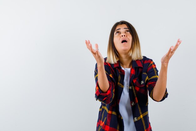 Yong woman opening her hands and begging on white background