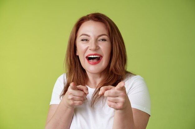 You did best friendly joyful enthusiastic redhead ginger middleaged female pointing index fingers camera finger pistol gesture smiling broadly congratulate cheer coworker stand green wall