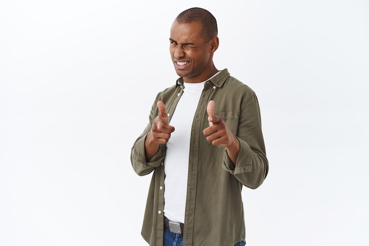 無料Photo おめでとうございます生意気なハンサムなアフリカ系アメリカ人男性の肖像画がウィンクし、笑顔でカメラピッキングで指を指して素晴らしい仕事を賞賛し、彼の選択を誰かをいちゃつく