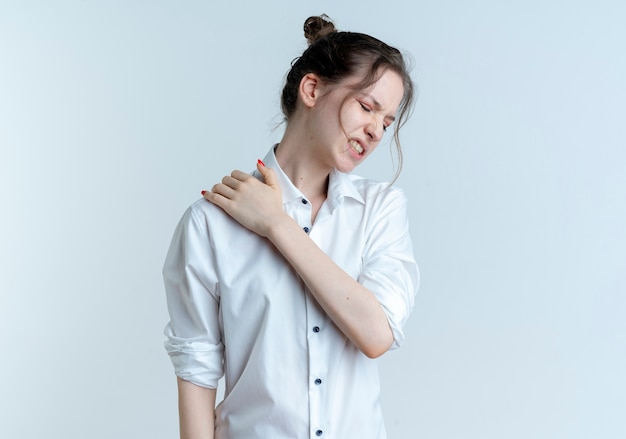 Free photo young aching blonde russian girl holds shoulder isolated on white space with copy space