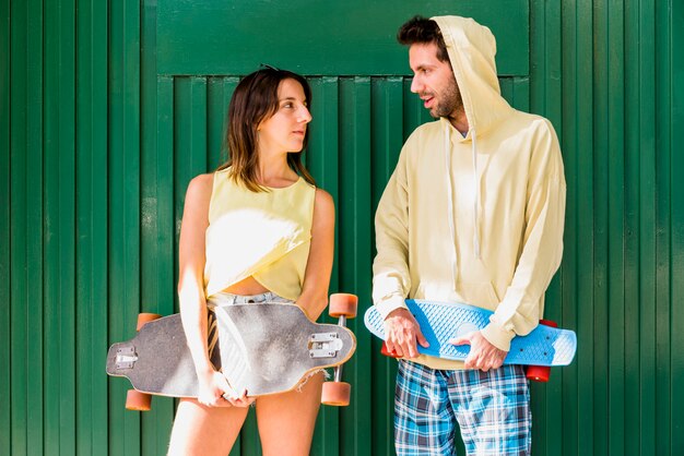 Young active couple of friends holding skateboards