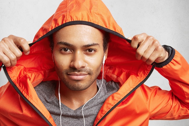 Young active mixed race man with dark skin and stubble, being wet after going in for sport on rainy weather