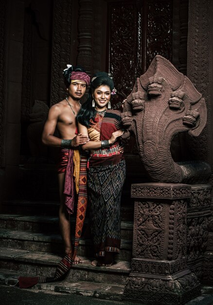 Young Actor and Actress wearing beautiful ancient costumes, in ancient monuments, dramatic style. Perform on legend love popular story, Thai Isan folktale called "Phadaeng and Nang-ai" in acient site