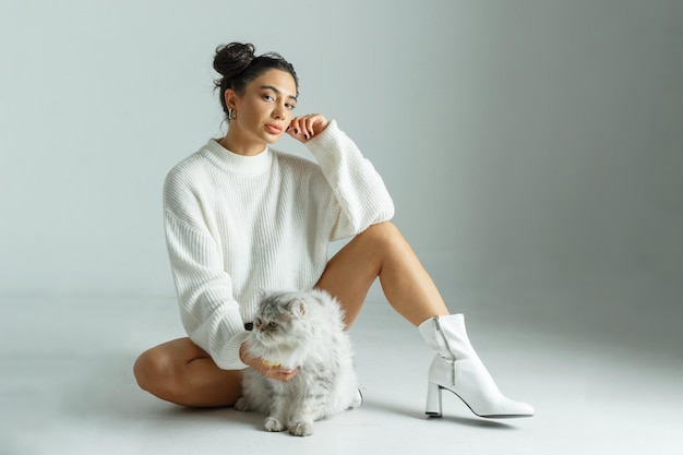 Young adorable girl sitting on the ground with her cat and looking at the camera High quality photo