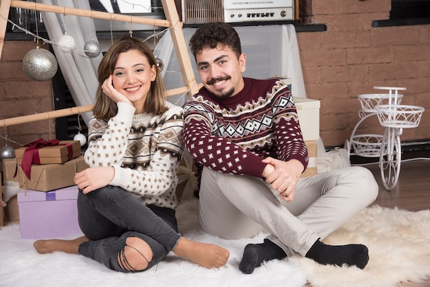 Young adorable smiling couple sitting on the floor and posing.