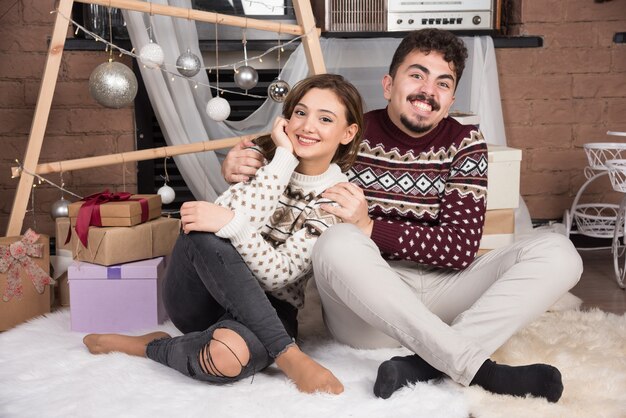 Young adorable smiling couple sitting on the floor and posing.