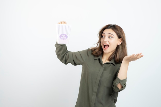 Молодая очаровательная женщина держит коробку с попкорном и позирует. Фото высокого качества