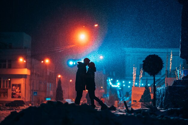 Молодая пара взрослых в объятиях друг друга на заснеженной улице