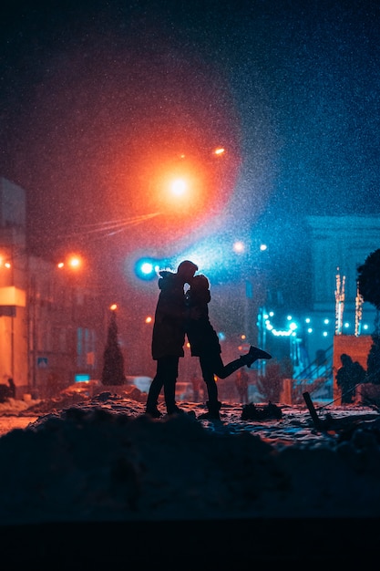 Young adult couple in each other's arms on snow covered street