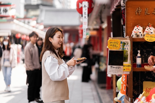 무료 사진 일본 길거리 음식을 즐기는 젊은 성인