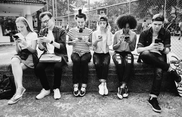 Young adult friends using smartphones together outdoors youth culture concept