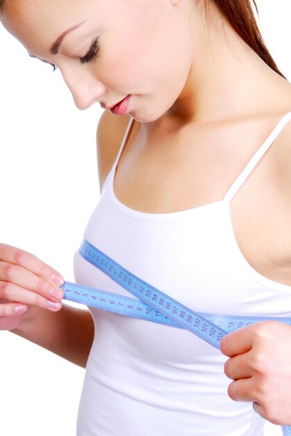 Young adult girl measuring her perfect breast -  isolated on a white background